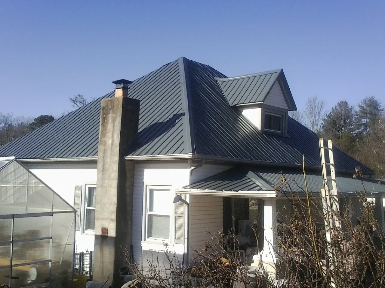 Dark blue standing seam metal roof on a white farmhouse with dormer — Slate & Tile Roof Repair by Roofing Brothers in Agra