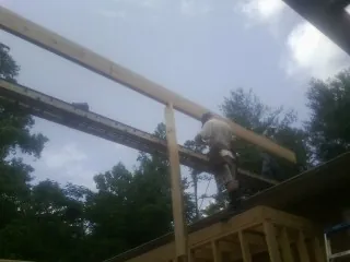 Carpenter setting a ridge beam over a new addition frame — Ice Dam Removal by Roofing Brothers in Agra