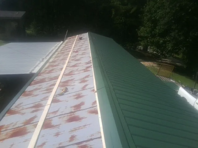 Old rusted panels beside newly installed green metal roofing — Wind Damage Roof Repair by Roofing Brothers in Agra