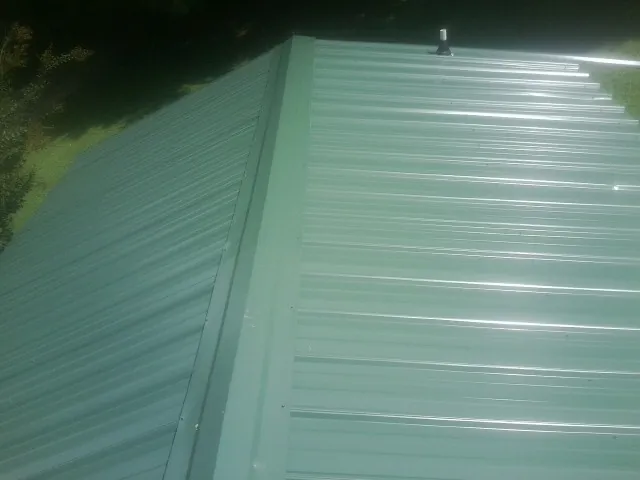 New green metal panels meeting at the ridge of a roof — Flat Roof Repair work by our crew in Agra