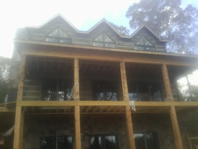 Dormers and porch framing on a large log home under construction — Roof Coating work by our crew in Agra