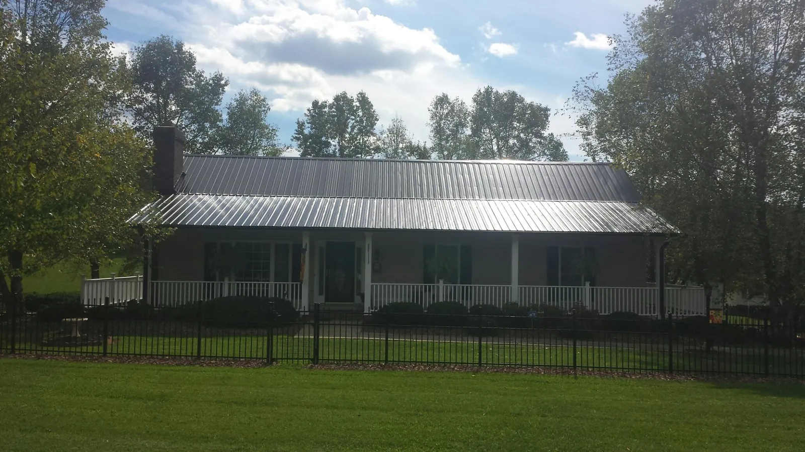 Gray metal roof on a brick ranch with a full width front porch — Gutter Guard Installation work by our crew in Agra
