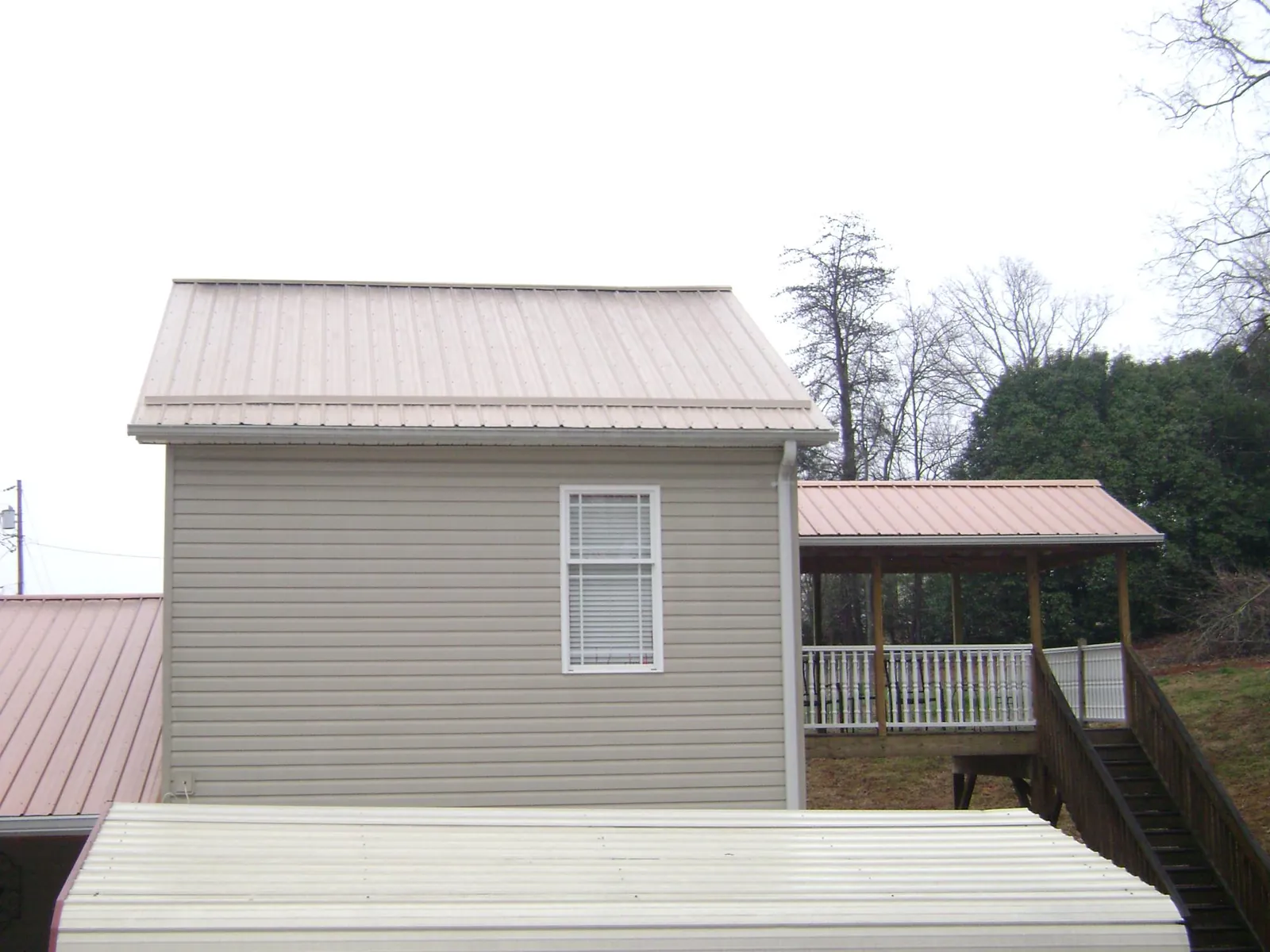 Tan metal roofs on a two story addition and attached porch, from a Roof Replacement job in Agra