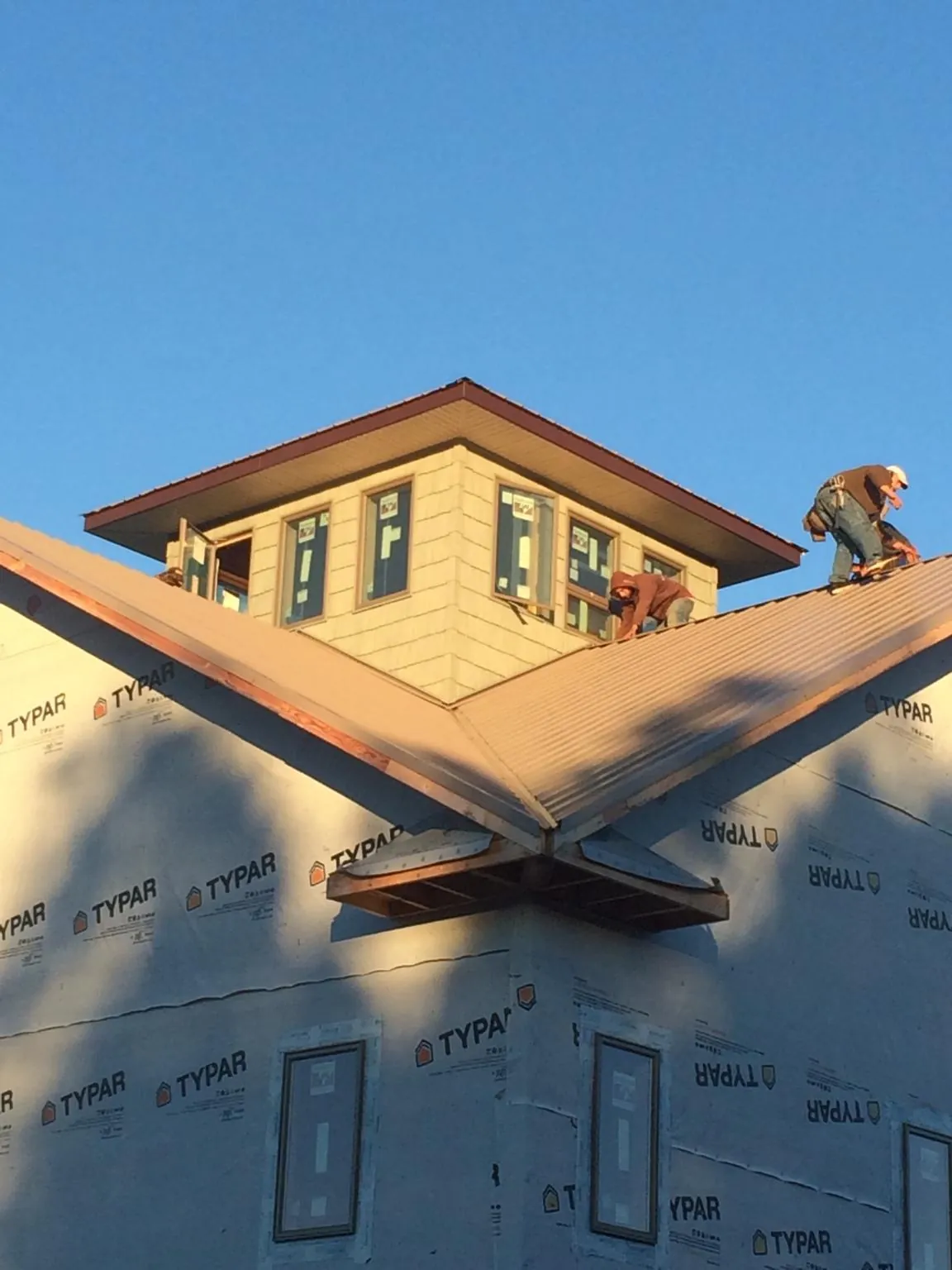 Roofers working around a rooftop cupola on a new metal roof at sunset — Roof Waterproofing in Agra by Roofing Brothers